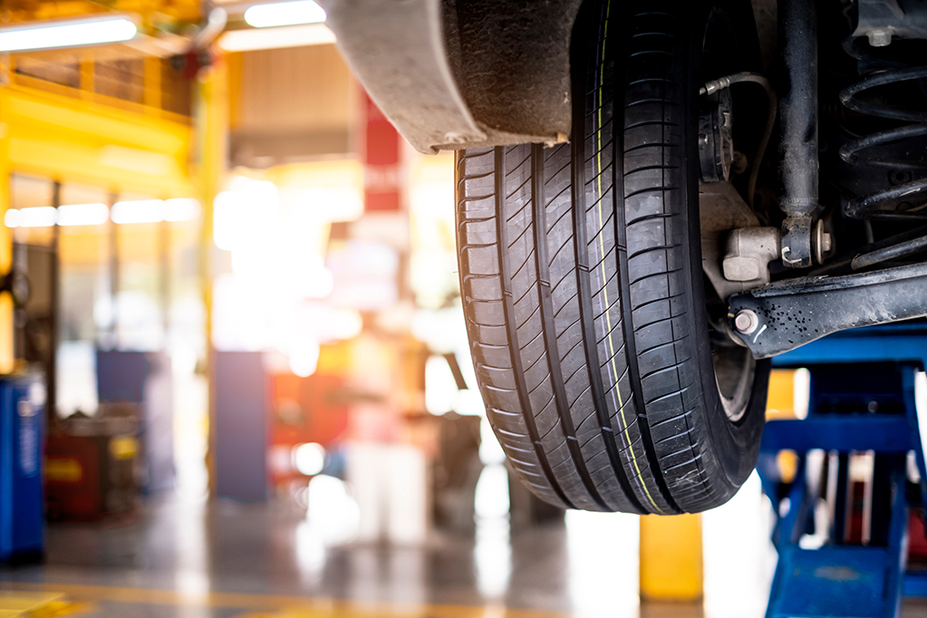 Car automobile mechanic working on repairing the wheel tire of vehicle, taking car in for service workshop for male car mechanic fixing problems replacing broken parts of using tools and equipment